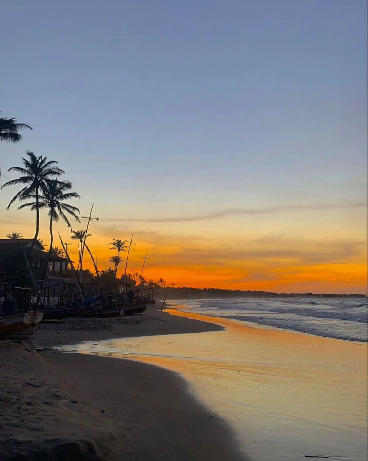 Pôr do sol na praia, com coqueiros e jangadas na areia